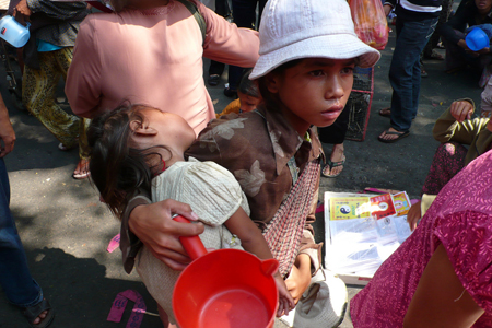 A young, impoverished boy is shown holding a baby girl.