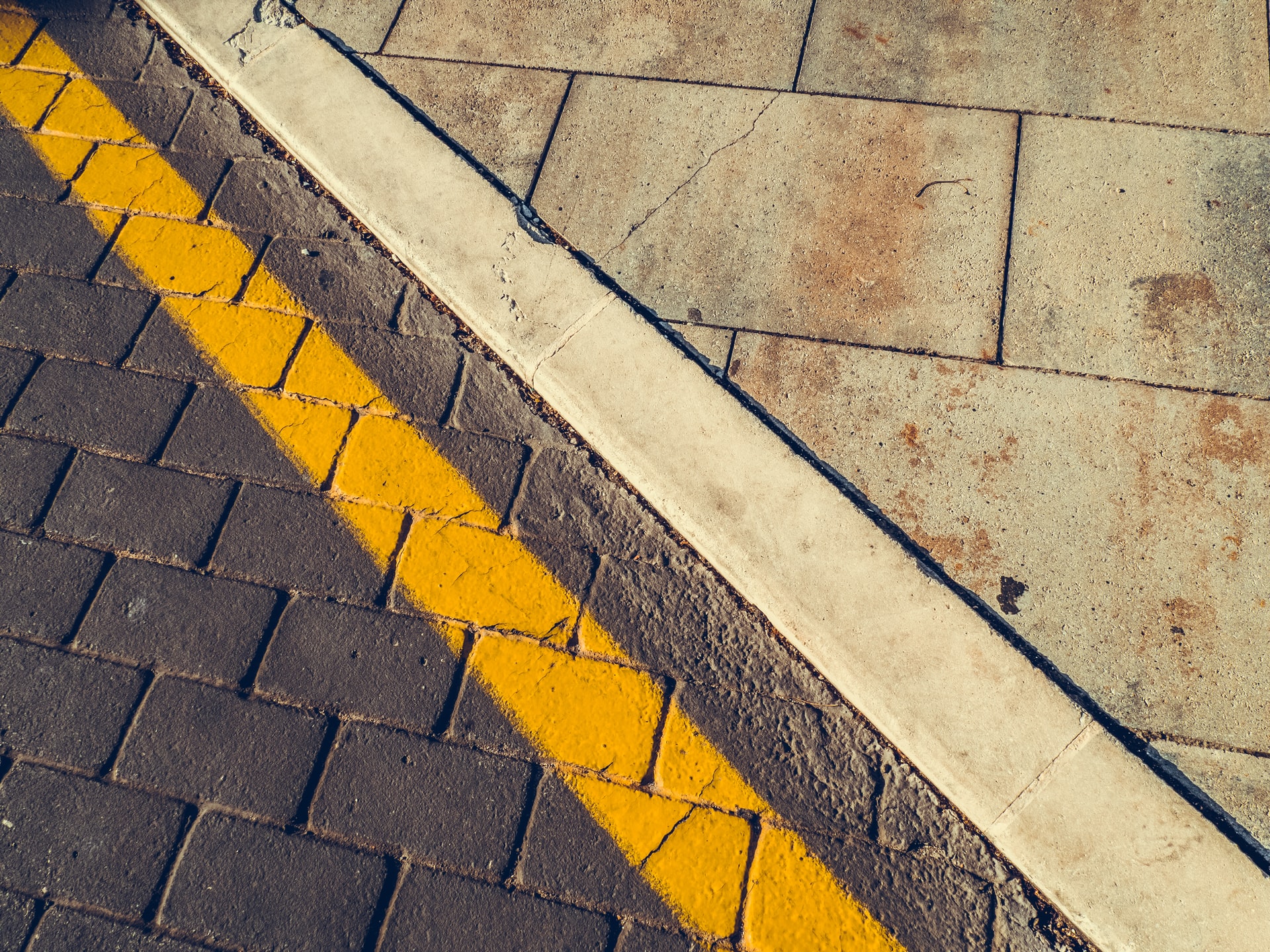 The line between road pavement and sidewalk pavement, emphasized by a painted yellow line.