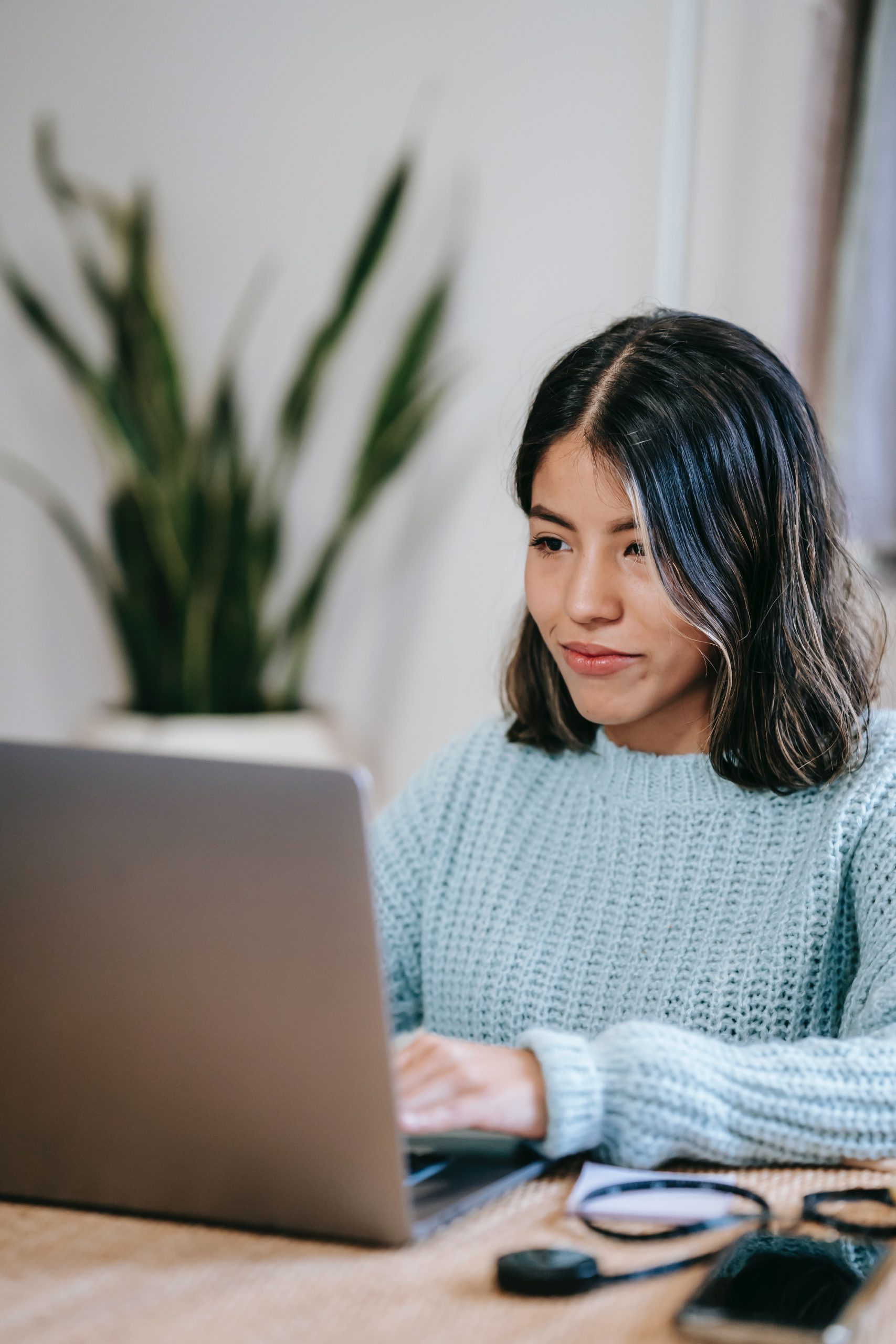 A Latin American woman works at a computer, looking confident.