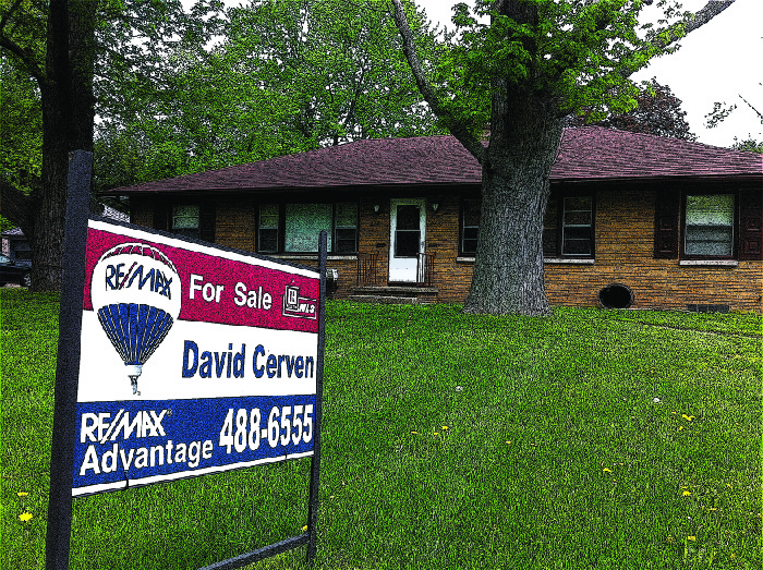 A photograph of a house with a “For Sale” sign in the front yard.