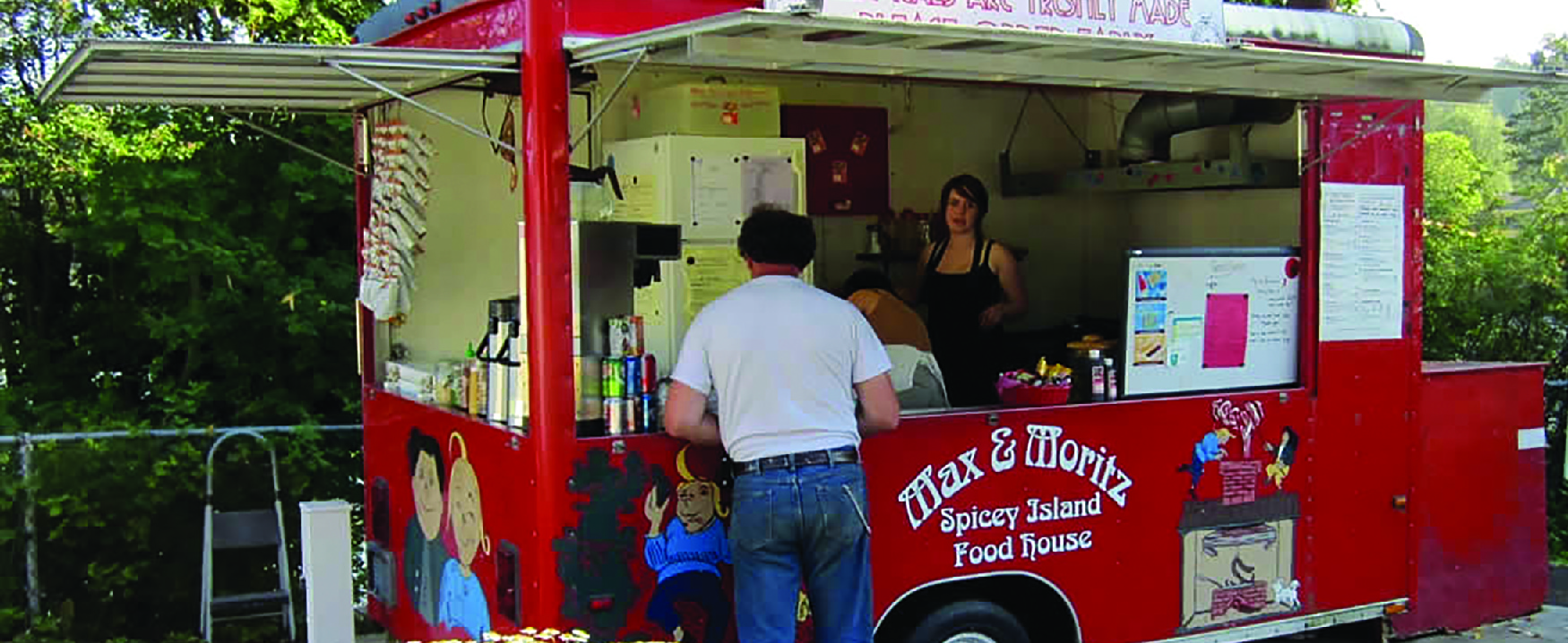 Picture of two people in a food truck serving a customer.