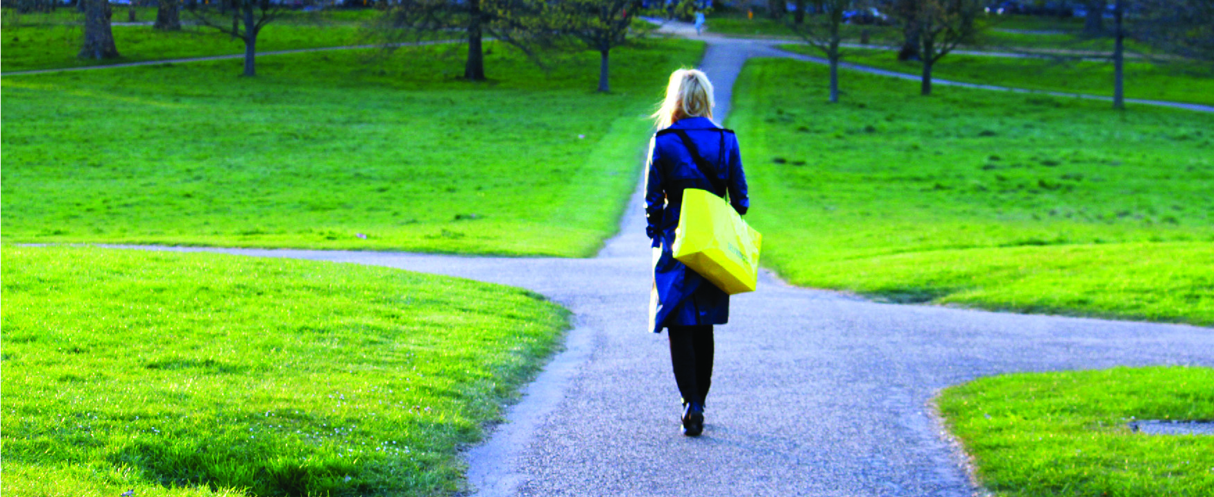 A photograph of a woman walking on a path that branches off in different directions.