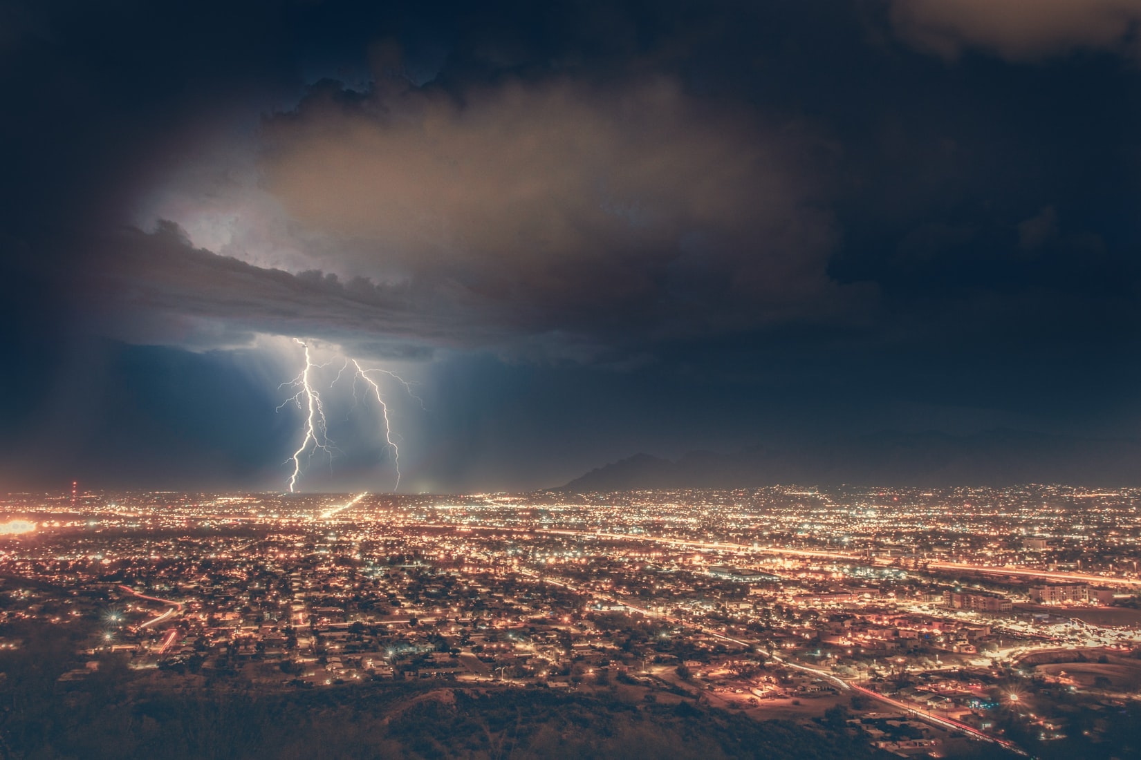 Lightning touches down over a city at night.