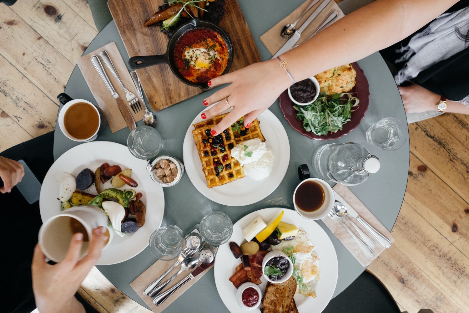 Ariel picture of a table full of breakfast food including waffles, fruit, breads, coffee, etc.